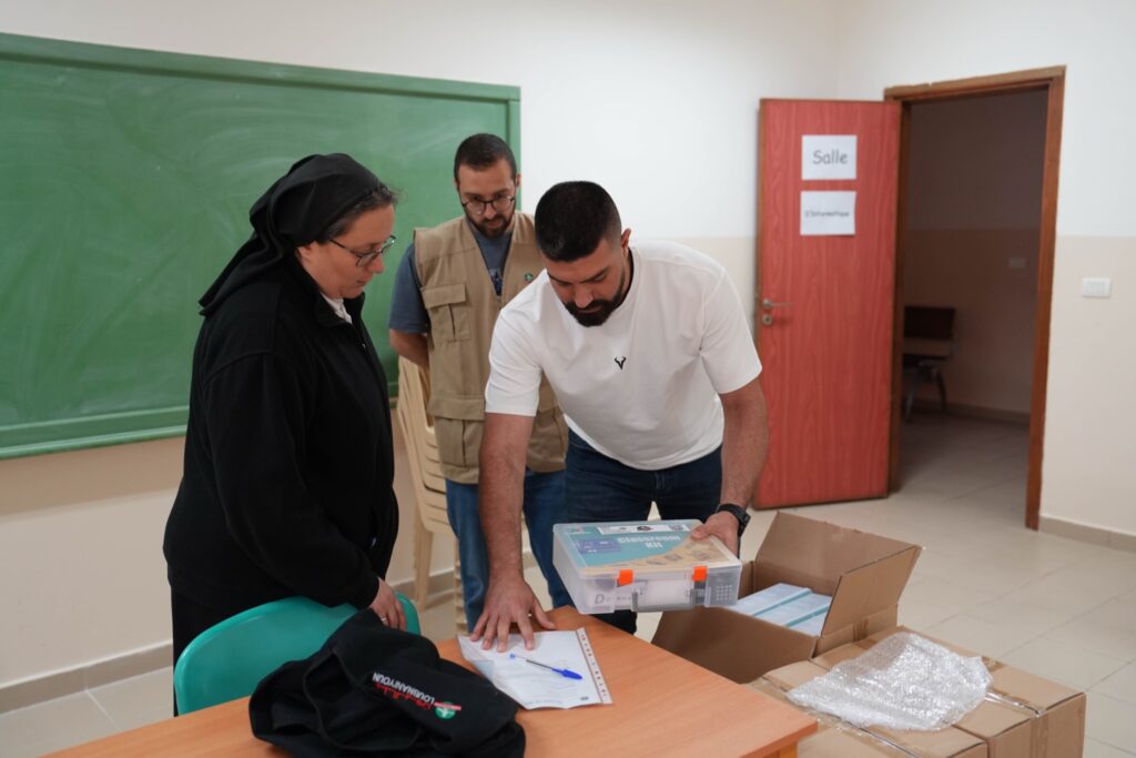 A nun and the Loubnaniyoun team unpacking an electronics kit in a school classroom