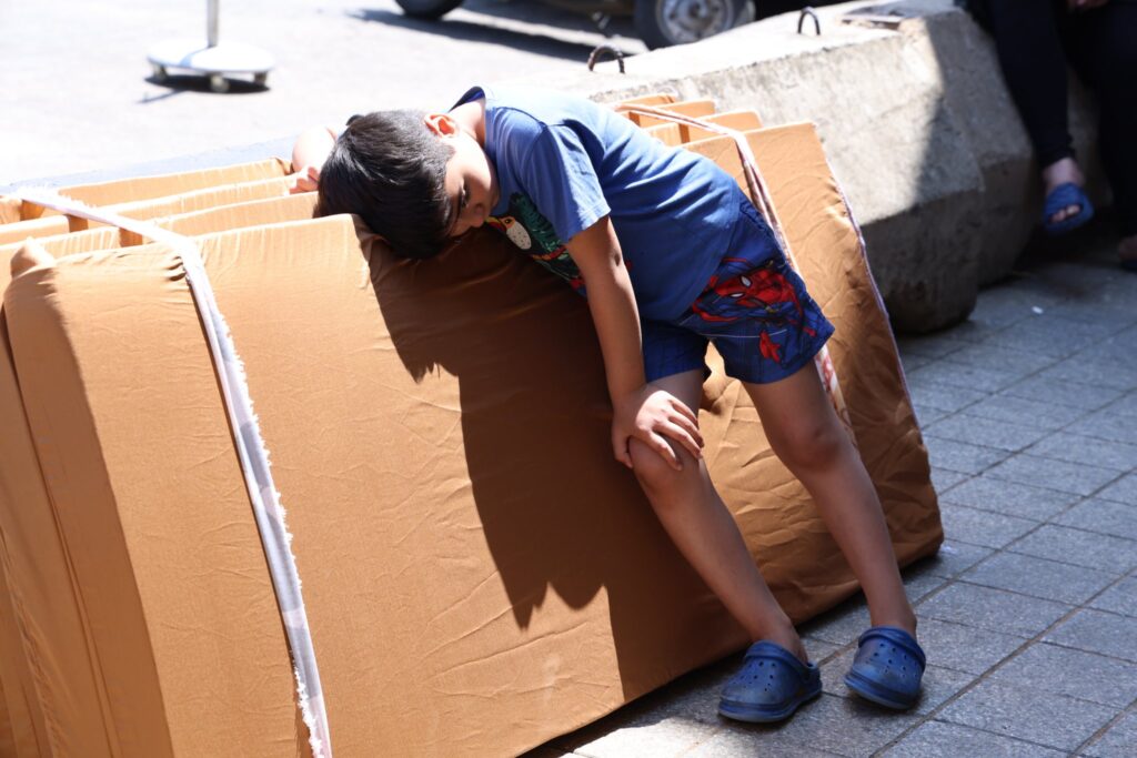 A boy resting on mattresses provided as emergency bedding