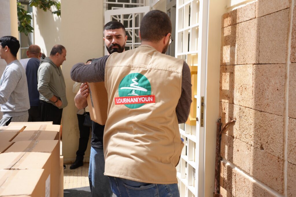 A Loubnaniyoun volunteer carrying an aid box into a shelter