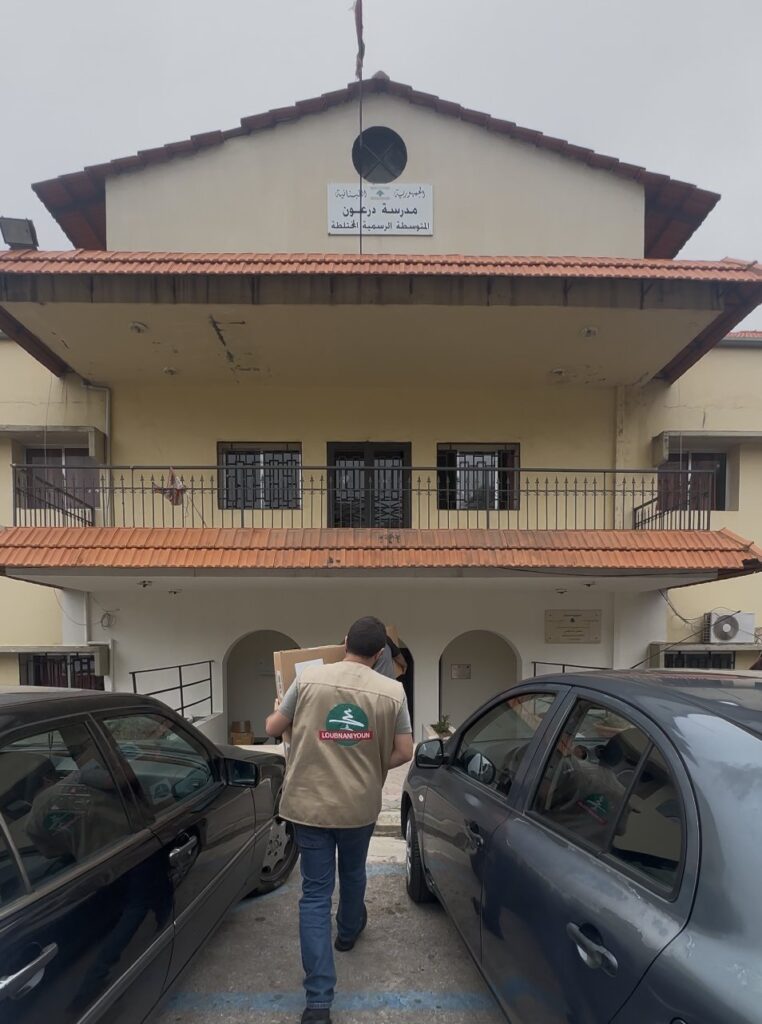 A volunteer delivering a food box to a public school sheltering displaced families