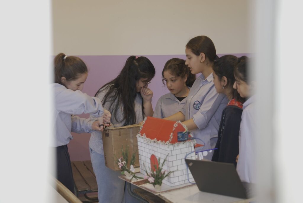 Schoolgirls presenting a model-house robotics project